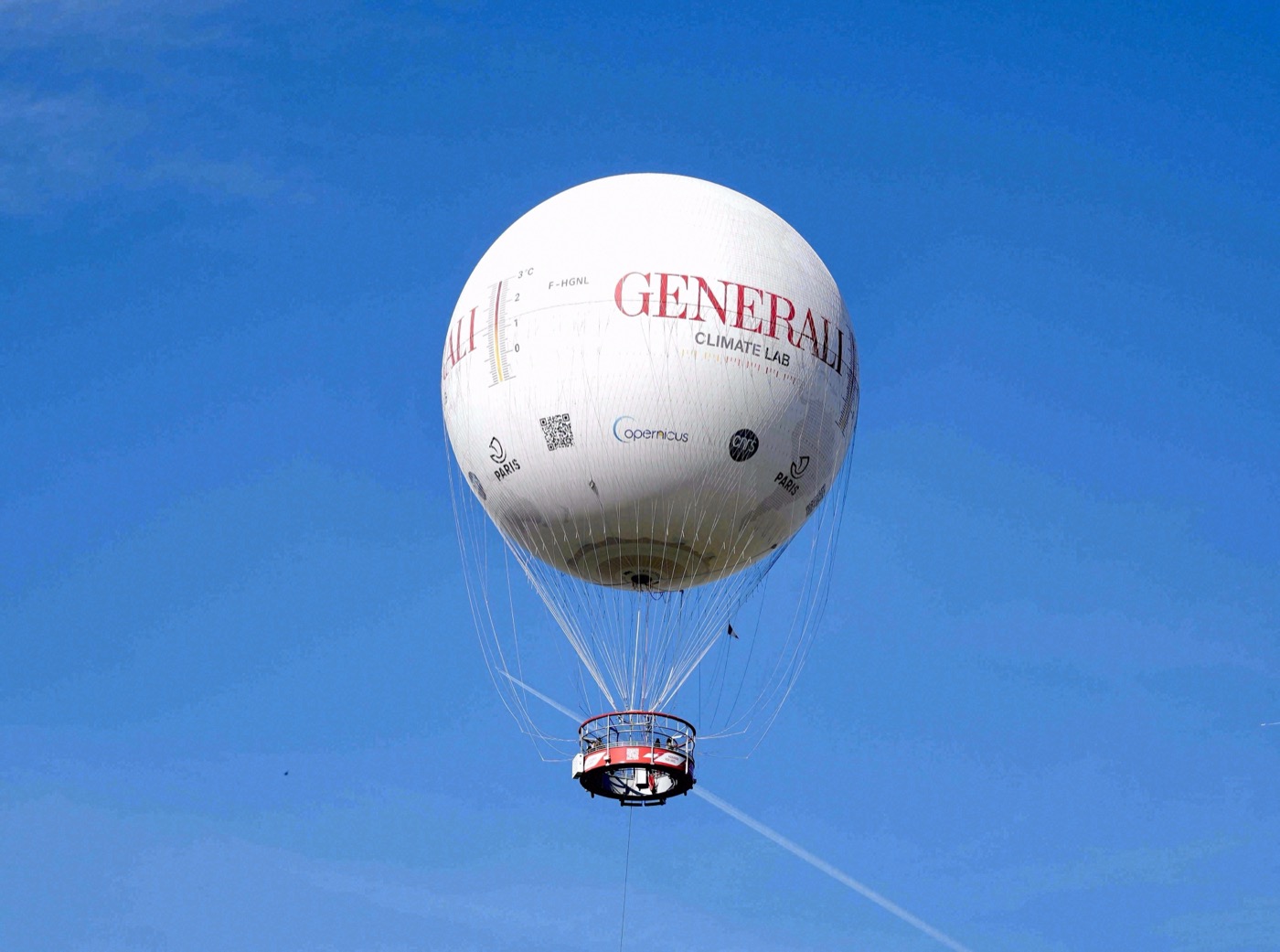 Der weiße Fesselballon Generali Climate Lab schwebt vor strahlend blauem Himmel über Paris.