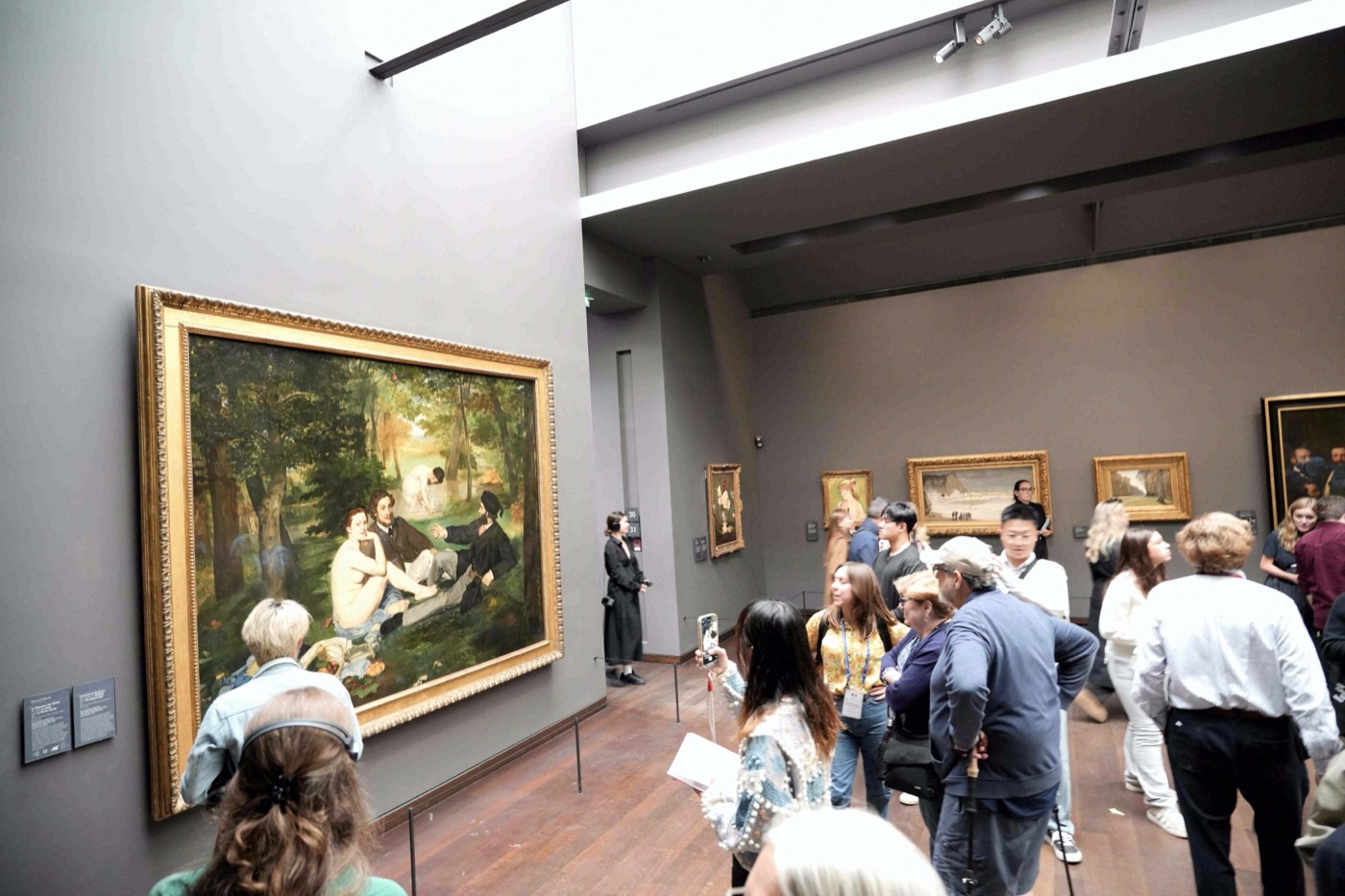 Besucher betrachten Édouard Manets großformatiges Gemälde „Le Déjeuner sur l'herbe“ in einem Saal des Musée