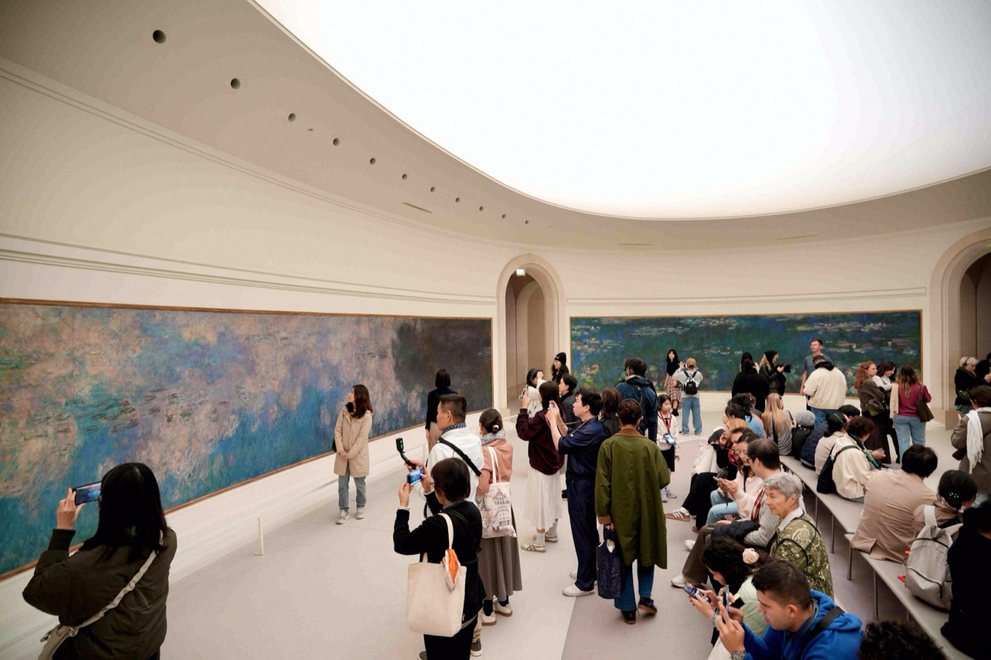 Besucher im ovalen Saal des Musée de l'Orangerie vor Monets riesigen Seerosenpanoramen.